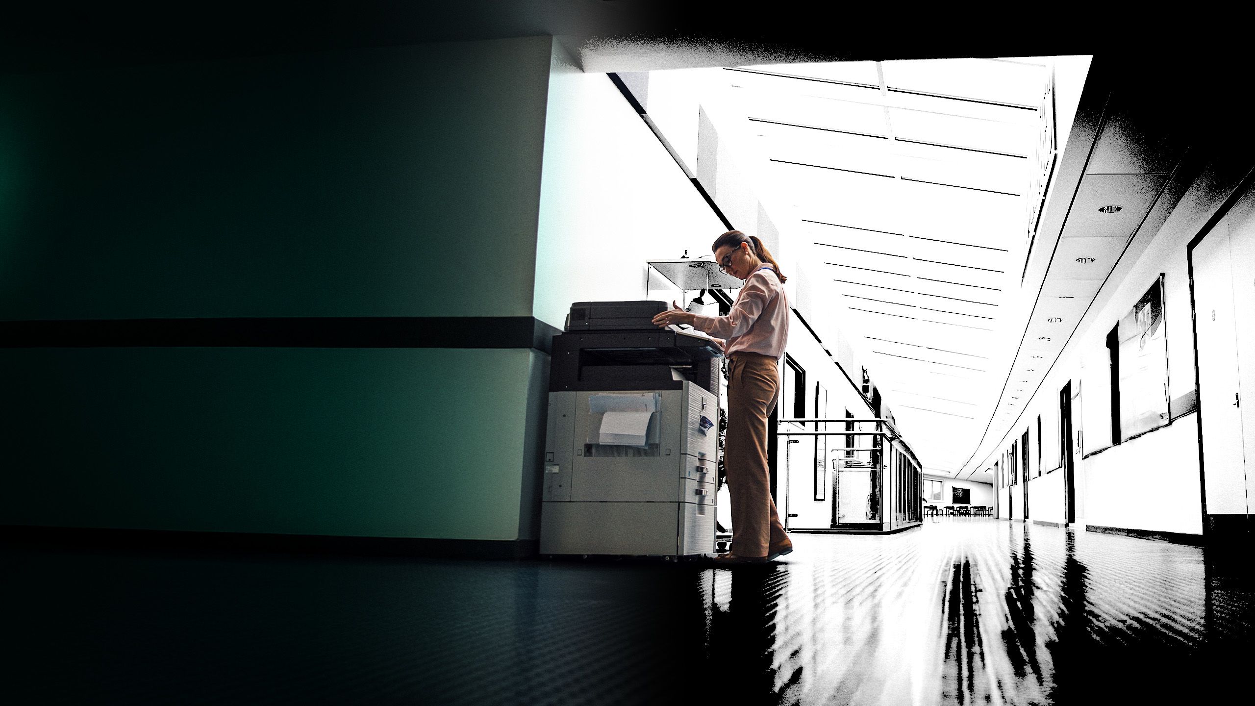 Teacher using a photocopier in a school hallway.